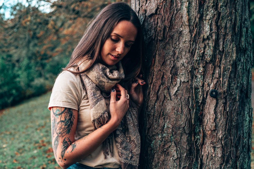 Frau steht am Baum und lächelt